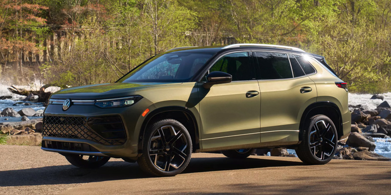 Green 2026 Volkswagen Tiguan driving near trees in Austin, TX
