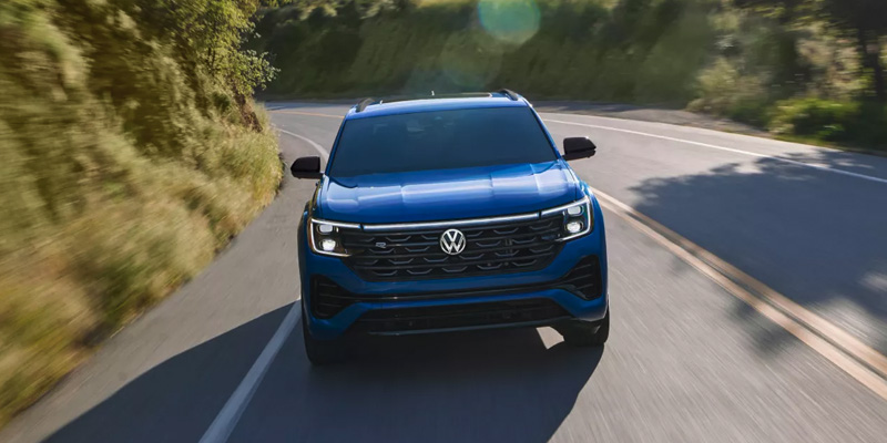 A blue Volkswagen SUV driving on a scenic road surrounded by greenery