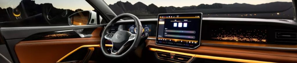 Interior of a 2026 Volkswagen vehicle showcasing dashboard and infotainment system with ambient lighting
