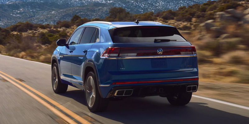 2026 Volkswagen Atlas Cross Sport driving on mountain road, rear-side view