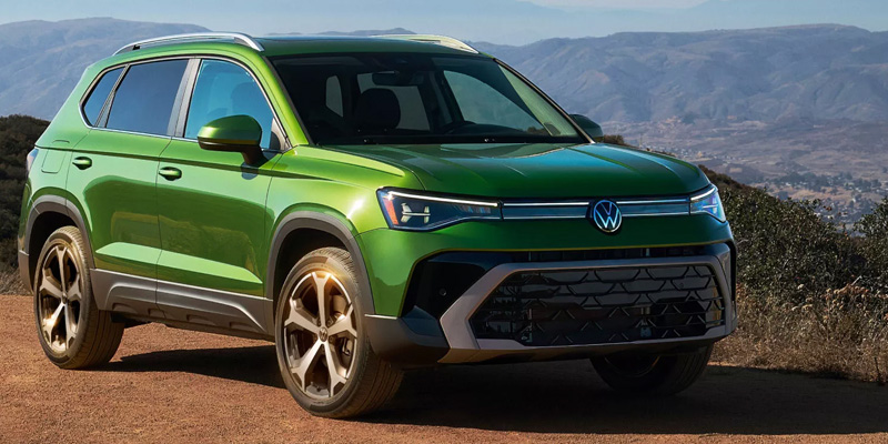 Green Volkswagen SUV parked in a scenic mountain landscape.