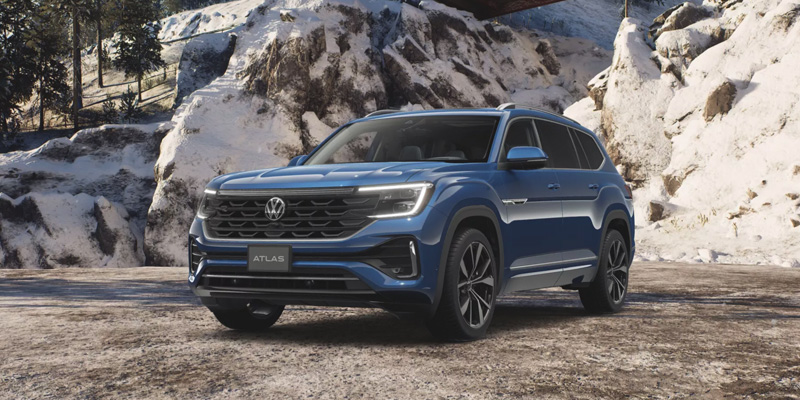 Blue Volkswagen Atlas SUV parked in a snowy mountain setting.