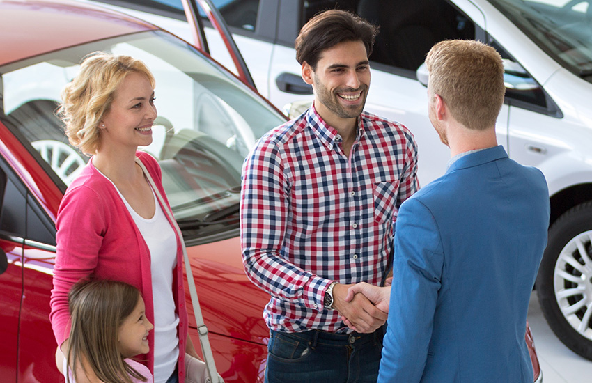 Customer and salesperson discussing a vehicle purchase at a dealership.
