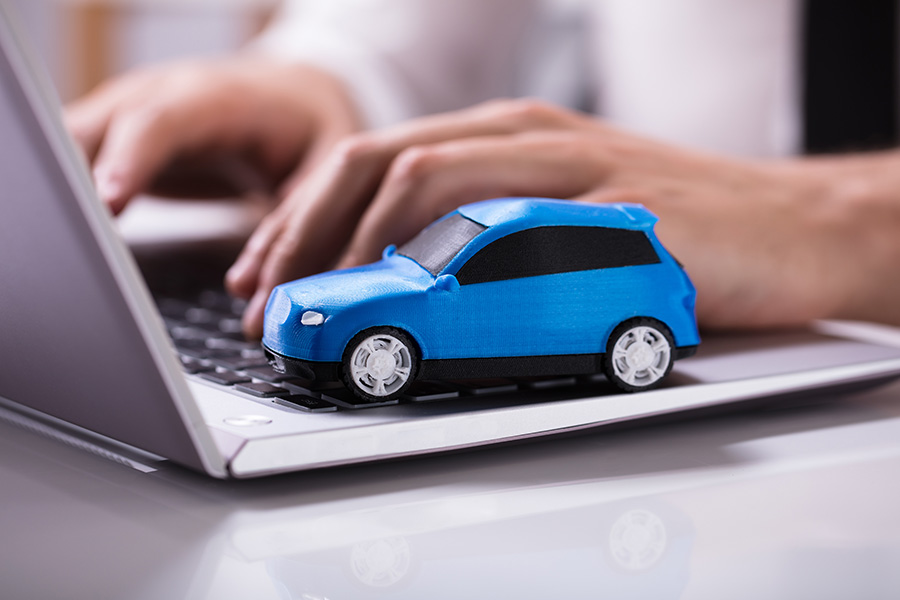 Toy blue car on a laptop keyboard, representing online car shopping.
