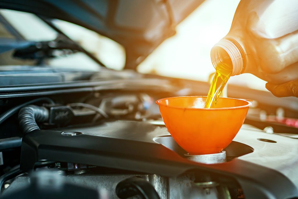 Motor oil being poured through a funnel into a vehicle engine.