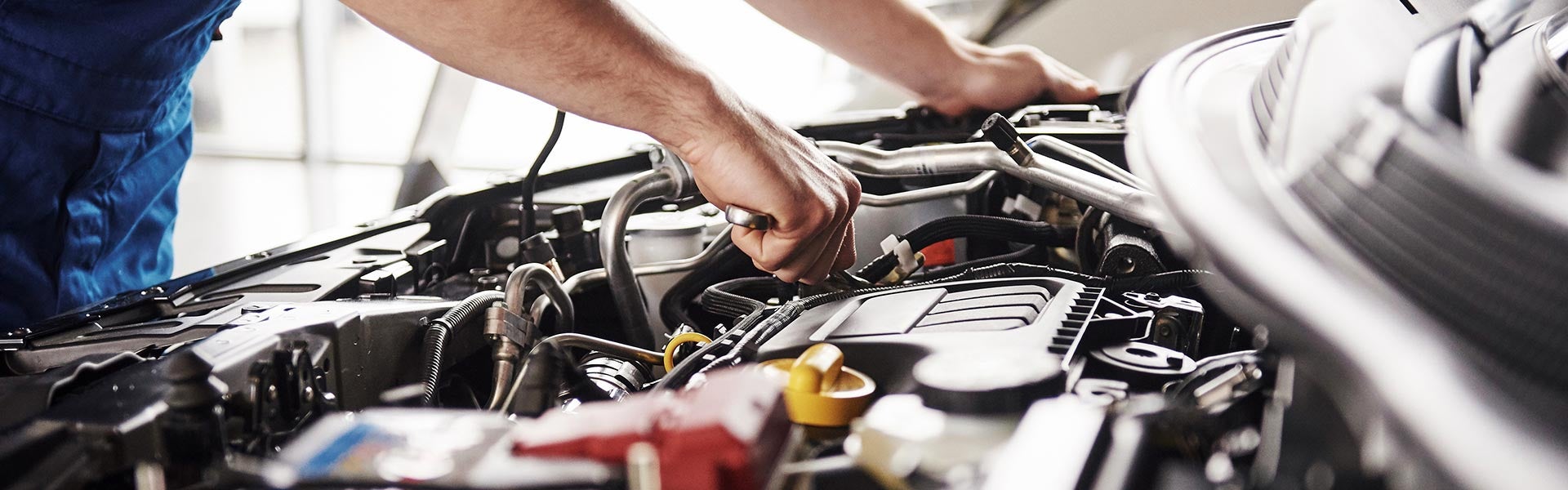 Mechanic inspecting a vehicle engine compartment during automotive maintenance or repair service.